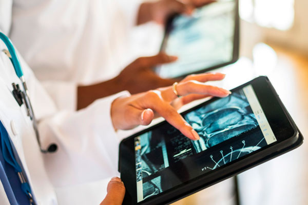 A physician looks at a CT image using a computer tablet.
