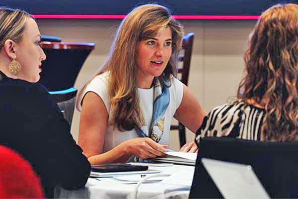 Three people sitting at a table converse.