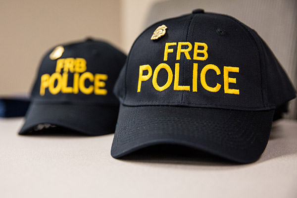 Two black baseball caps embroidered with "FRB Police" in yellow thread.