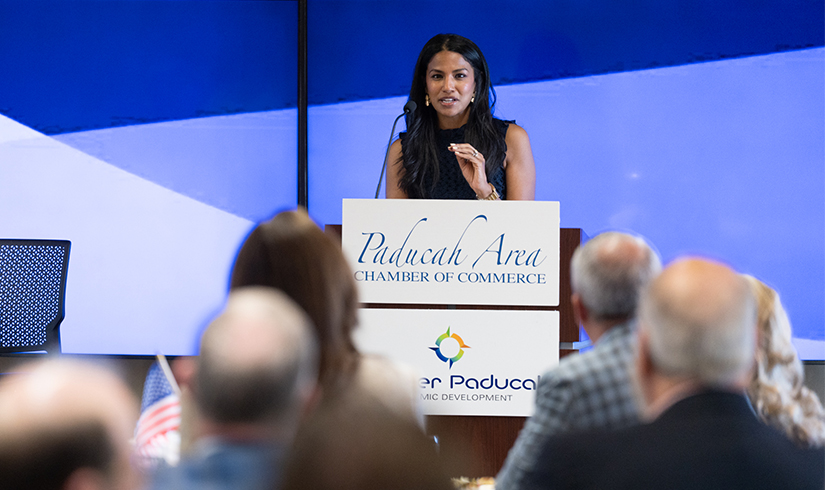 St. Louis Fed Louisville Regional Executive Seema Sheth stands at a podium in the front of a room, presenting to an audience.