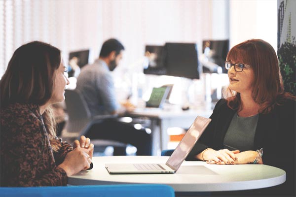 Two people speaking at a round table.