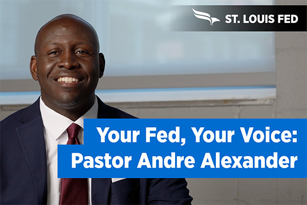 Pastor Andre Alexander smiles next to a 'Your Fed, Your Voice' banner.