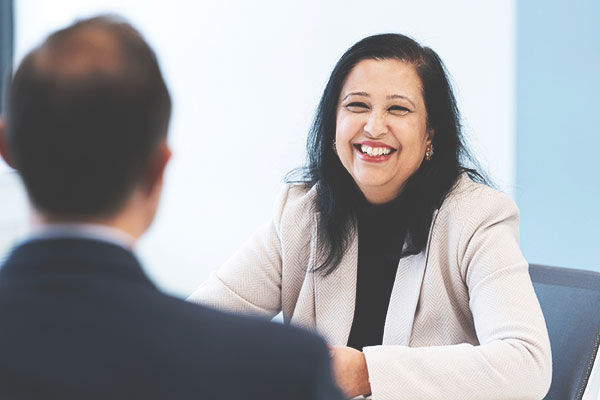 Woman smiles as she sits across from a colleague.