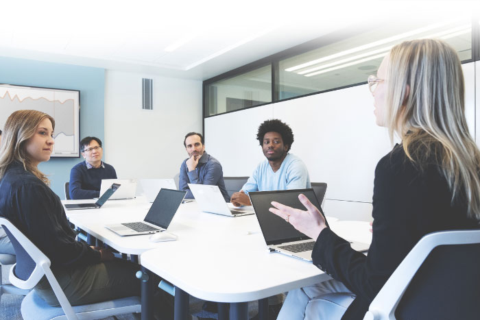 Group of economists and research associates exchange ideas in a brightly lit room.